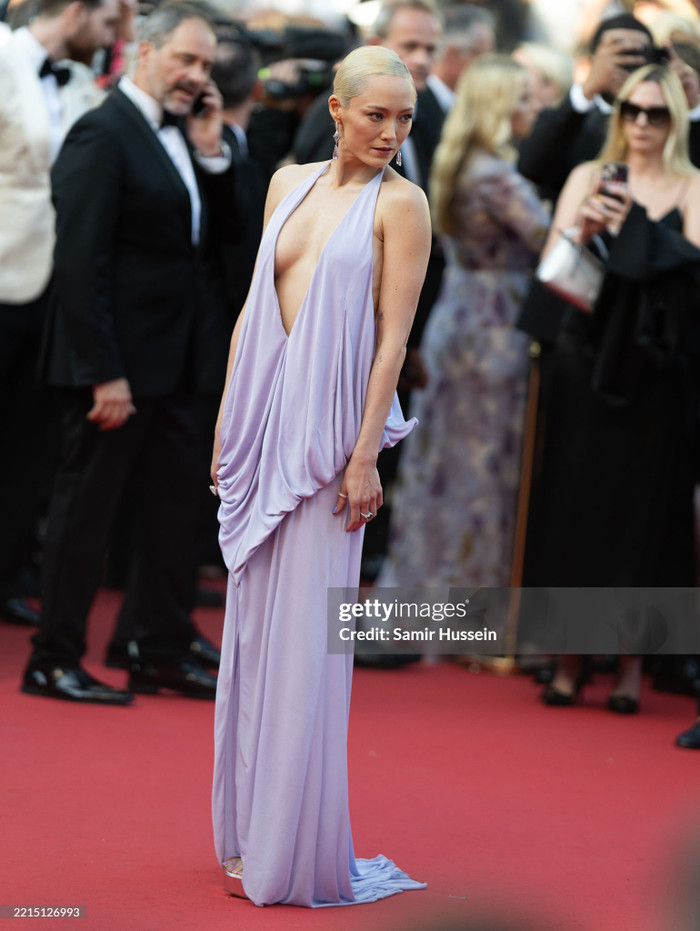 Pom Klementieff đầy gợi cảm tại Cannes 2025 với mẫu đầm tím nhạt xẻ ngực sâu, chất liệu mềm rủ ôm nhẹ cơ thể. Thiết kế cổ yếm kết hợp tà váy xếp nếp tinh tế càng tôn lên vẻ quyến rũ lạnh lùng của nữ diễn viên “Guardians of the Galaxy”. Mái tóc bạch kim vuốt gọn cùng khuyên tai dài tạo tổng thể thanh thoát, sang trọng.
